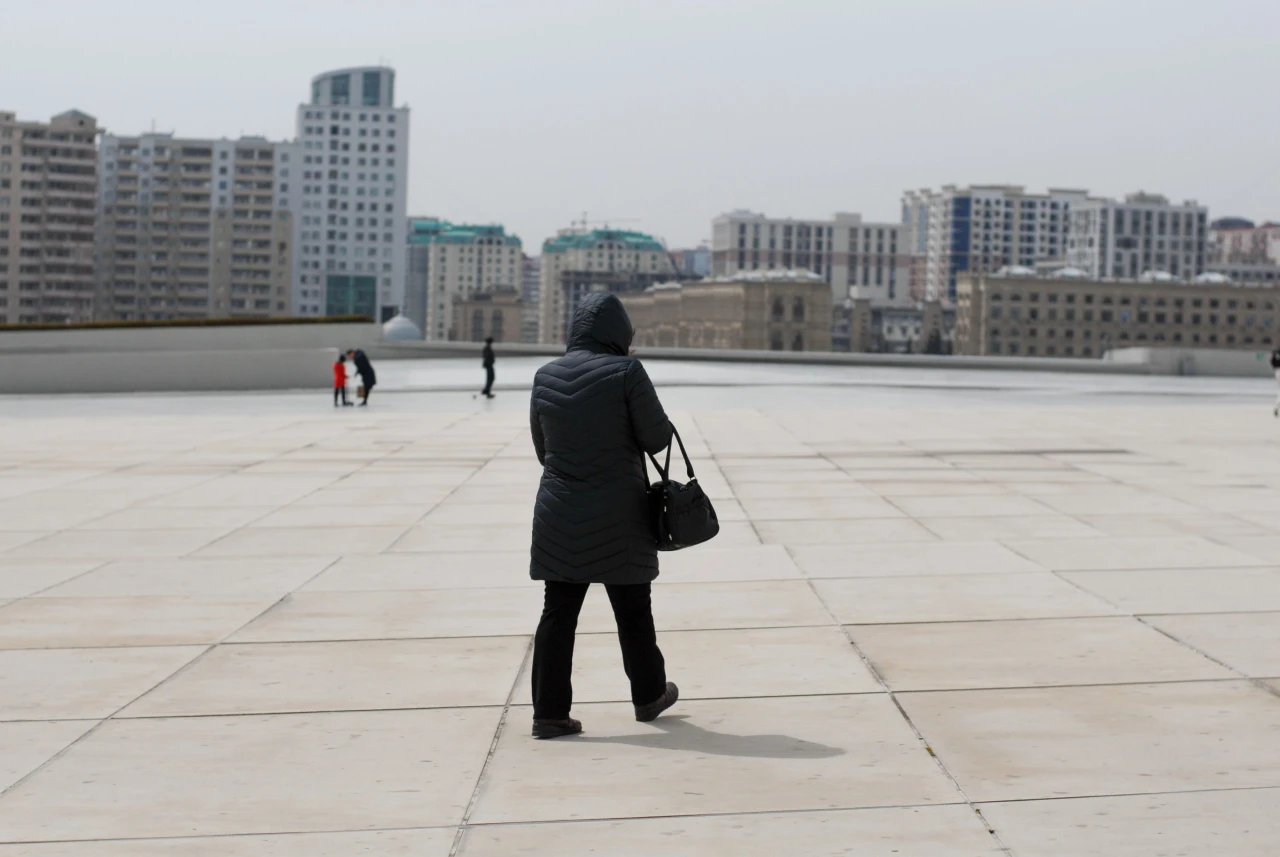 Solo female traveler walking through a city plaza with her luggage